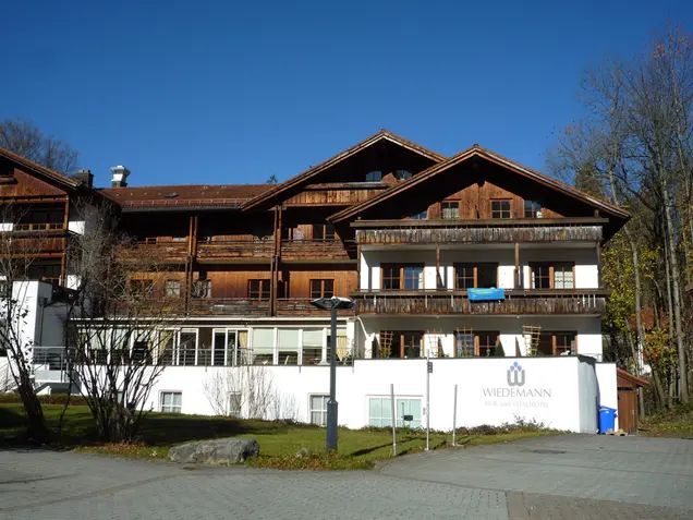 Hotelgebäude mit dunklen Holzbalkonen vor der Renovierung